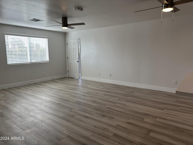 empty room featuring ceiling fan, hardwood / wood-style flooring, and a textured ceiling