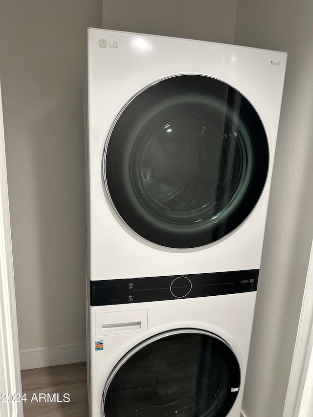 clothes washing area featuring stacked washer / drying machine and hardwood / wood-style floors