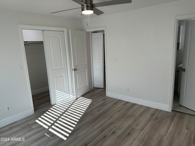 unfurnished bedroom with ceiling fan, a closet, and hardwood / wood-style floors