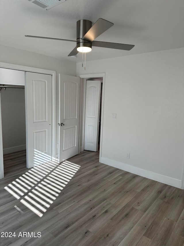 unfurnished bedroom featuring hardwood / wood-style floors, a closet, and ceiling fan