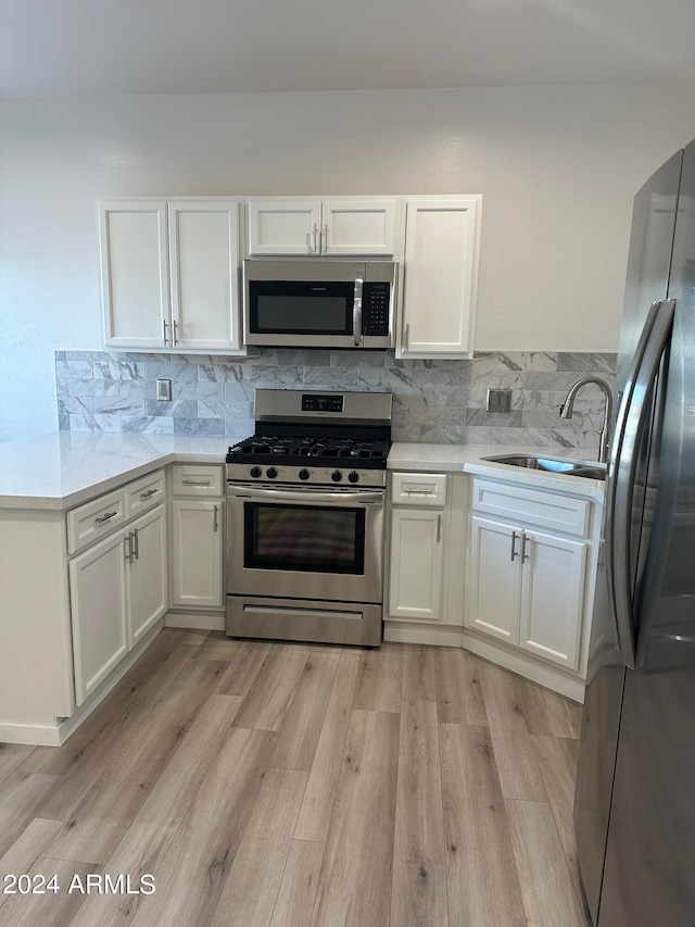 kitchen with stainless steel appliances, decorative backsplash, and light hardwood / wood-style flooring