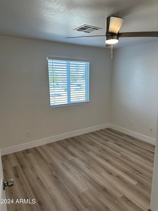 spare room with ceiling fan, a textured ceiling, and wood-type flooring