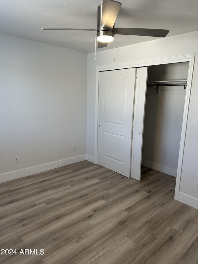 unfurnished bedroom featuring ceiling fan, a closet, and wood-type flooring