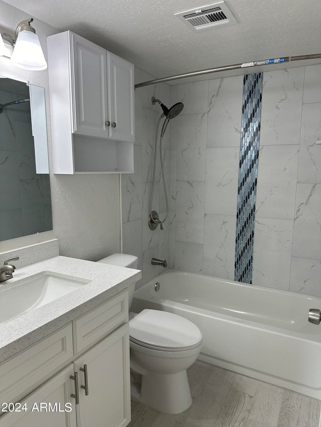 full bathroom featuring tiled shower / bath, toilet, a textured ceiling, and vanity