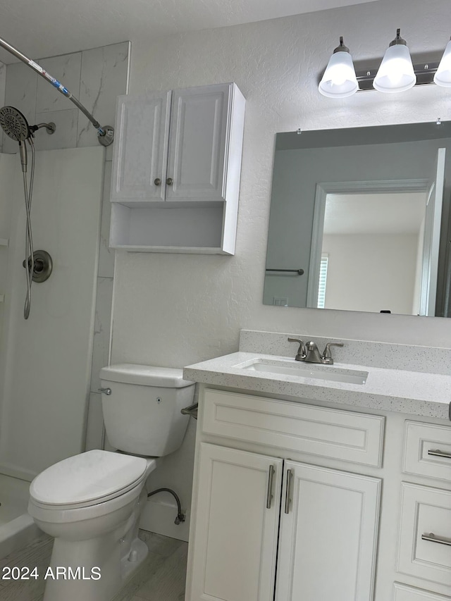 bathroom with toilet, a shower, and vanity