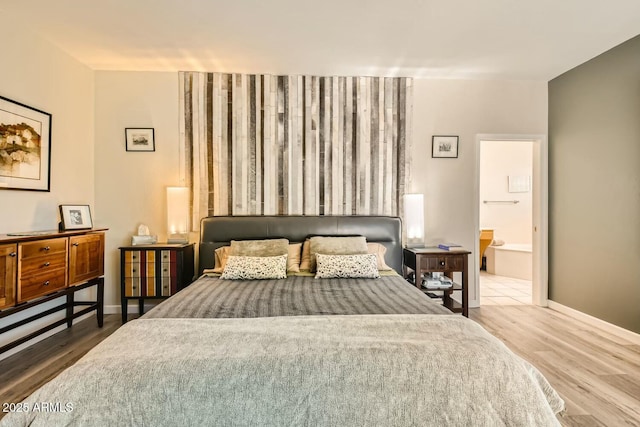 bedroom with ensuite bath and hardwood / wood-style floors