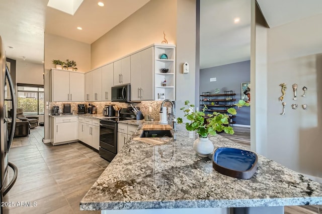 kitchen with range with electric stovetop, sink, white cabinets, and kitchen peninsula