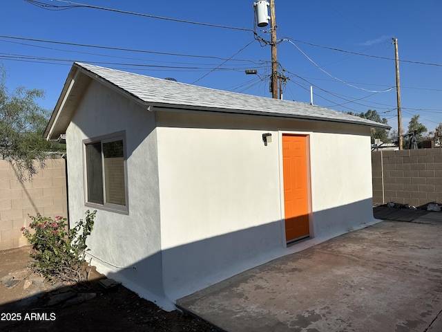 view of home's exterior with fence, stucco siding, a patio area, and roof with shingles