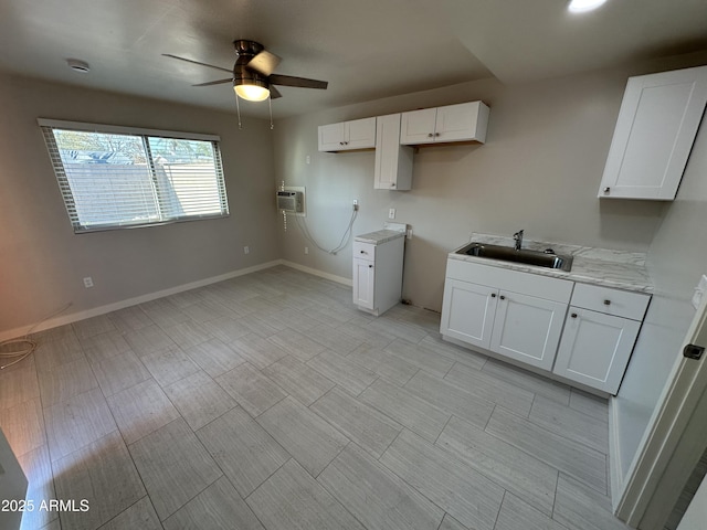 kitchen featuring a sink, ceiling fan, white cabinetry, and a wall mounted AC