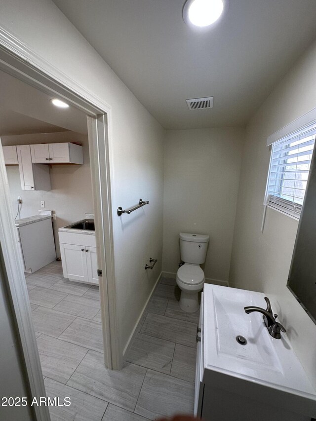 bathroom with toilet, vanity, tile patterned floors, and baseboards