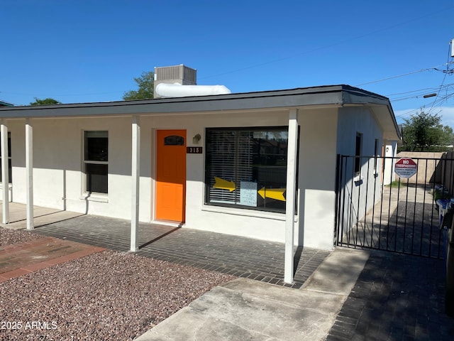 view of front of home featuring fence, a gate, stucco siding, and a porch