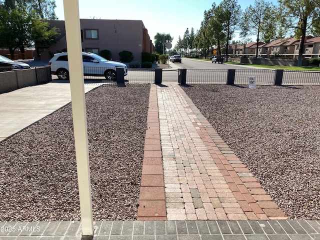 view of yard featuring a residential view, fence, and concrete driveway
