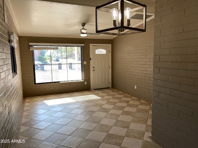 entrance foyer with brick wall, light tile patterned flooring, ornamental molding, and a chandelier