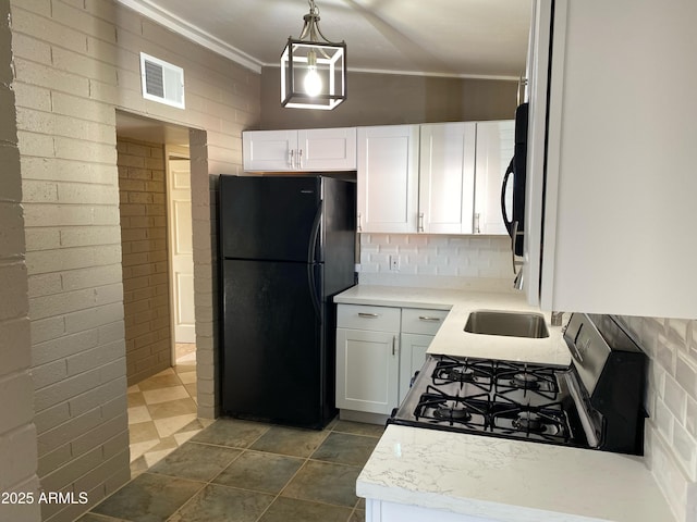 kitchen featuring freestanding refrigerator, gas range oven, white cabinetry, light countertops, and ornamental molding