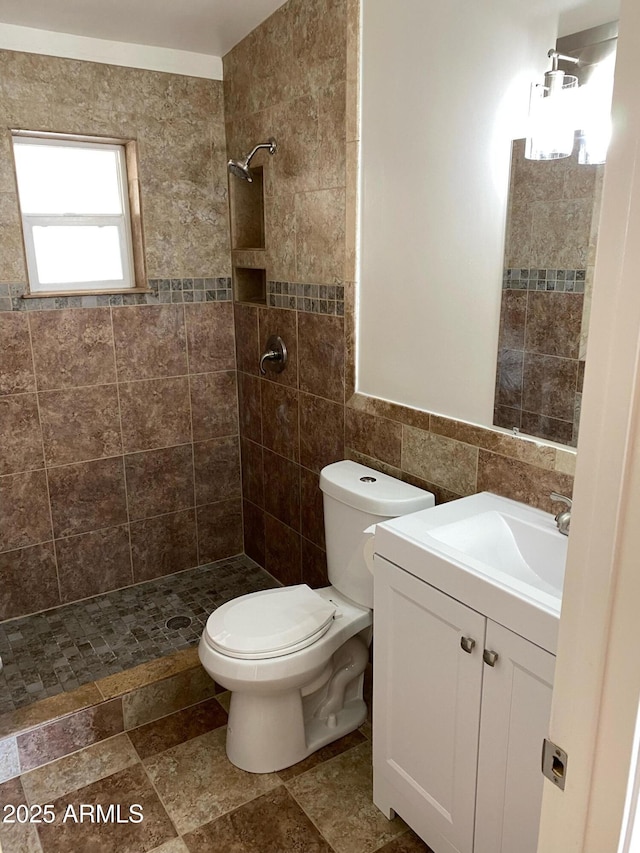 full bathroom featuring tile walls, a tile shower, toilet, and vanity