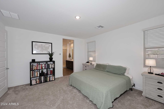 bedroom with ensuite bath and light carpet