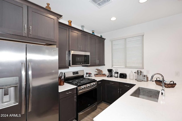 kitchen featuring stainless steel appliances, light hardwood / wood-style flooring, dark brown cabinets, and sink