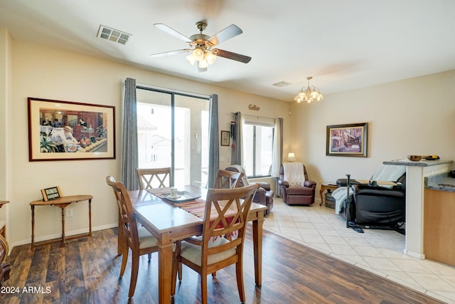 dining space with ceiling fan with notable chandelier and light hardwood / wood-style flooring