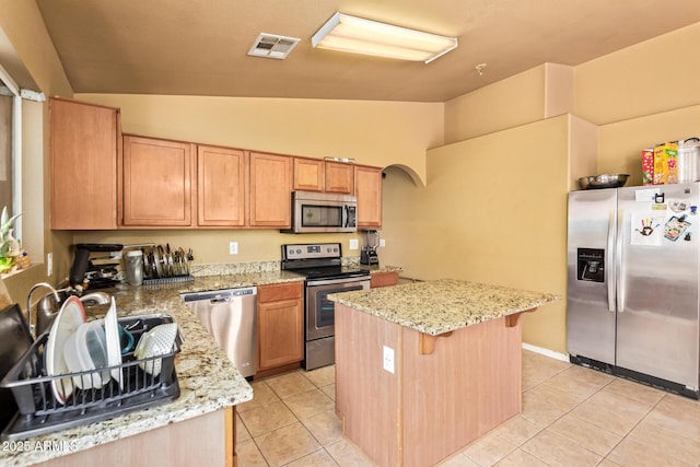 1619 E Aspen Ave, Buckeye, AZ 85326 - kitchen with stainless steel appliances, a center island, light tile patterned floors, arched walkways, and high vaulted ceiling