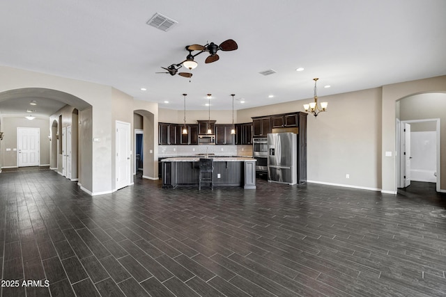 unfurnished living room with ceiling fan with notable chandelier