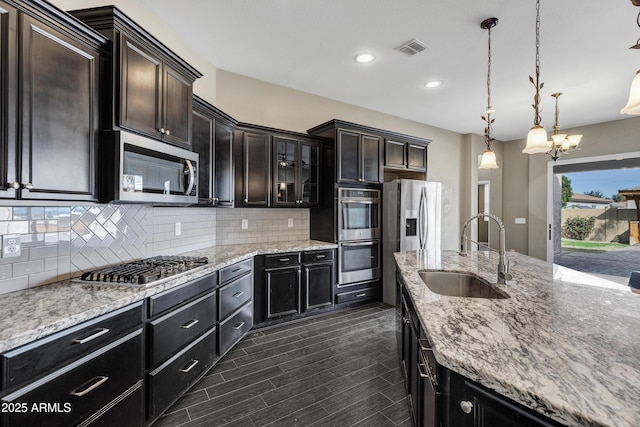 kitchen featuring pendant lighting, dark brown cabinetry, appliances with stainless steel finishes, and sink