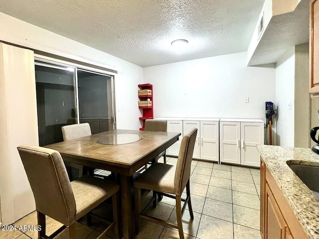 tiled dining area with sink and a textured ceiling