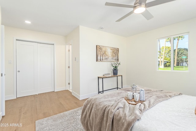 bedroom featuring ceiling fan, a closet, and light wood-type flooring