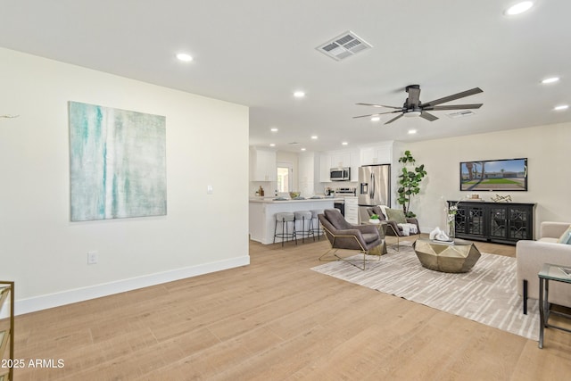 living room featuring light hardwood / wood-style flooring and ceiling fan