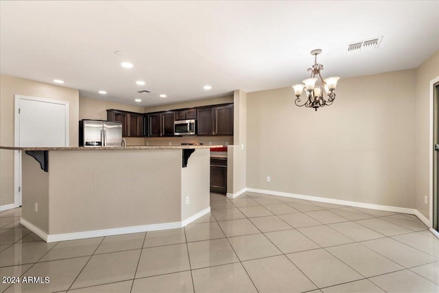 kitchen with dark brown cabinets, light tile patterned flooring, light stone counters, stainless steel appliances, and a chandelier