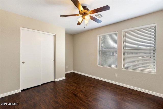 unfurnished bedroom with ceiling fan, dark hardwood / wood-style floors, and a closet