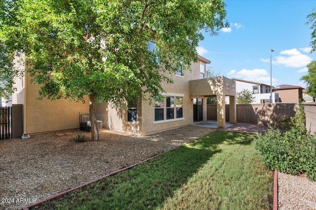 rear view of house featuring a yard and a patio