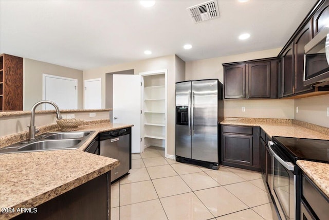 kitchen with sink, light tile patterned flooring, stainless steel appliances, and dark brown cabinets