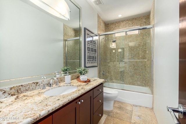 full bathroom with enclosed tub / shower combo, vanity, and toilet