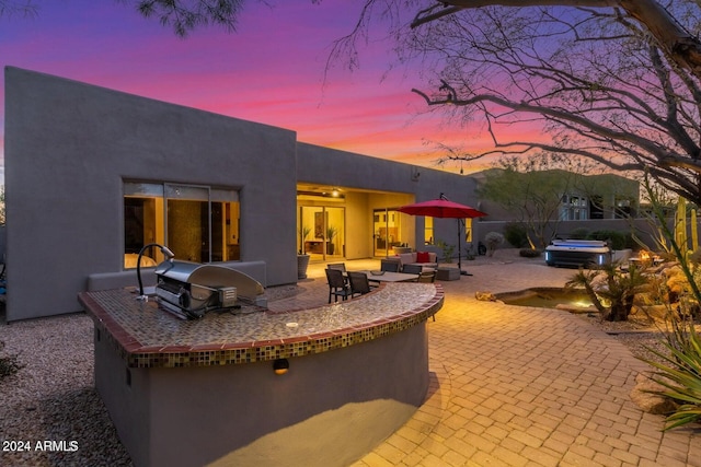 back house at dusk featuring area for grilling, a patio, and an outdoor living space