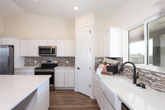 kitchen featuring lofted ceiling, backsplash, appliances with stainless steel finishes, dark hardwood / wood-style flooring, and white cabinetry