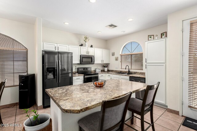 6505 S 15th Dr, Phoenix, AZ 85041 - kitchen with stainless steel appliances, a sink, a breakfast bar, a kitchen island, and white cabinetry