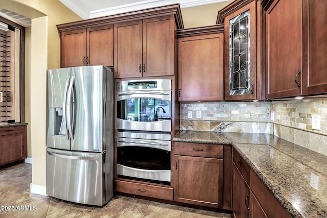 kitchen featuring stainless steel appliances, tasteful backsplash, dark stone countertops, glass insert cabinets, and crown molding