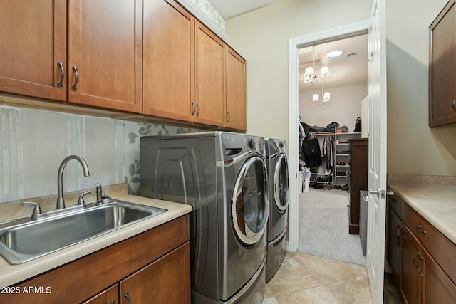 laundry area featuring a chandelier, washing machine and dryer, light carpet, a sink, and cabinet space