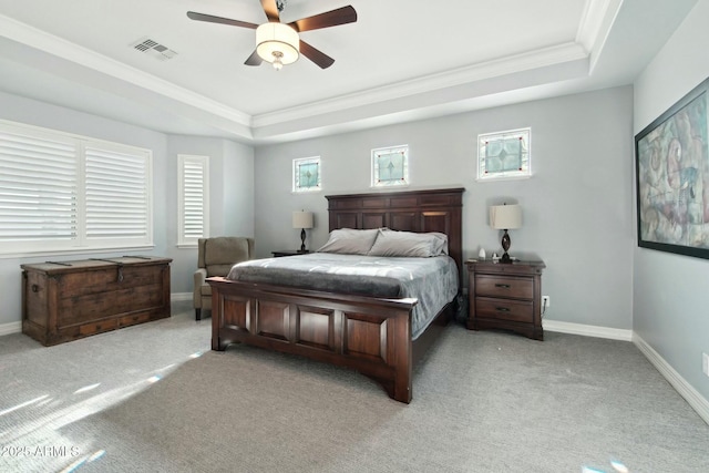 bedroom featuring light carpet, a tray ceiling, visible vents, and baseboards