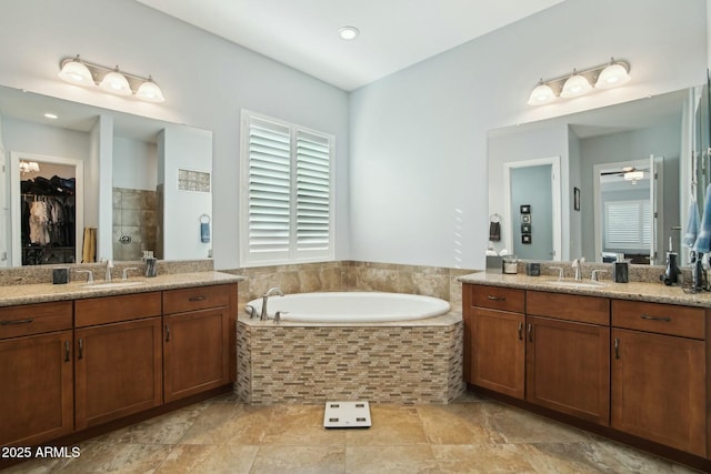 full bath with a garden tub, two vanities, a sink, and tiled shower