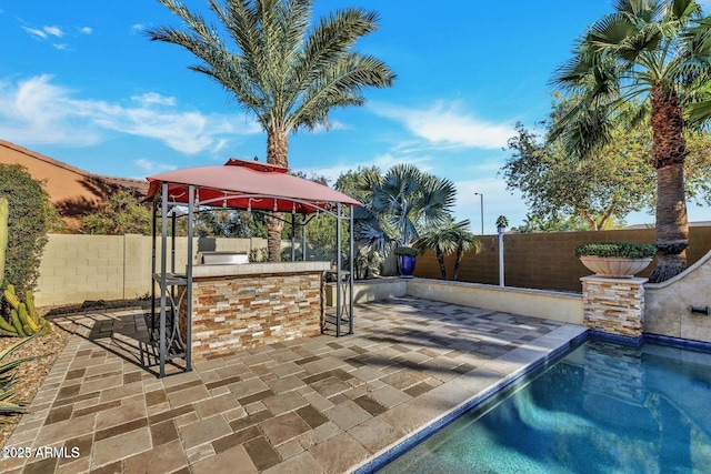 exterior space with a patio, an outdoor kitchen, a fenced backyard, outdoor dry bar, and a gazebo