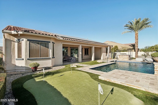 back of house featuring a patio, a fenced backyard, a tile roof, a fenced in pool, and stucco siding