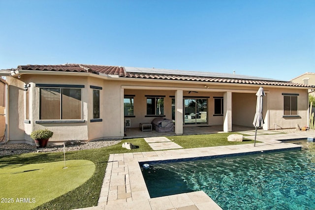 back of property with an outdoor pool, a patio area, a tile roof, and stucco siding