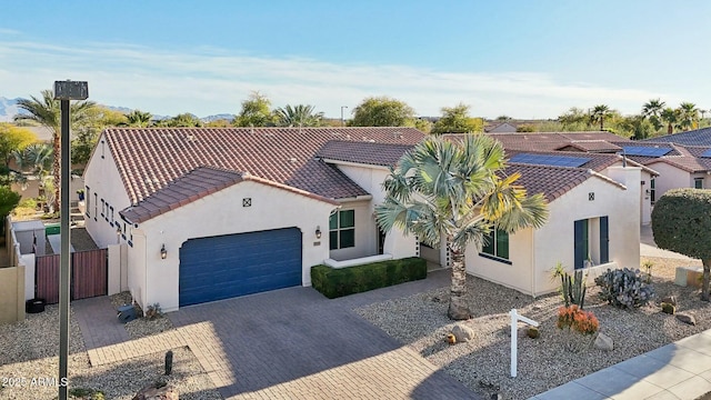 mediterranean / spanish home featuring a garage, decorative driveway, a tile roof, and stucco siding