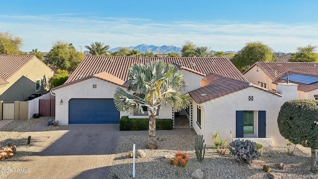 mediterranean / spanish-style house with an attached garage, fence, a tile roof, decorative driveway, and stucco siding