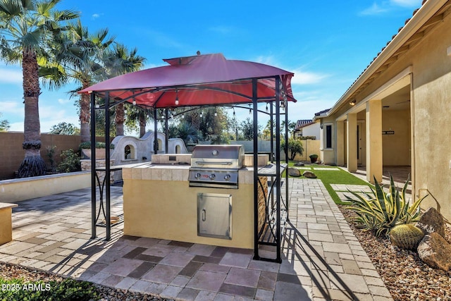 view of patio / terrace featuring exterior kitchen, a fenced backyard, a gazebo, and area for grilling