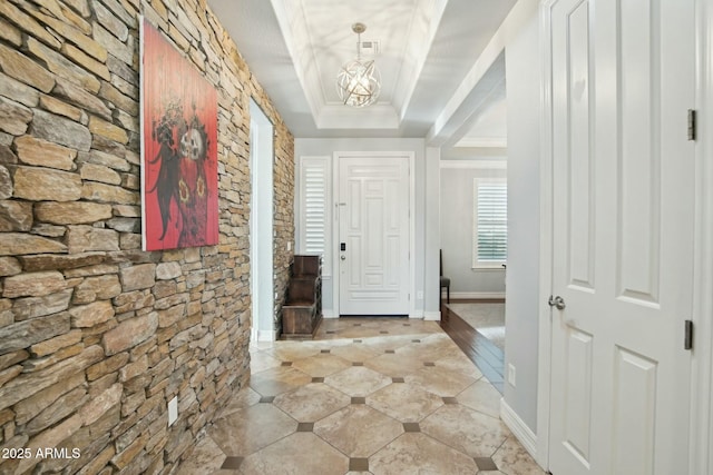 interior space featuring a tray ceiling, crown molding, a notable chandelier, light tile patterned floors, and visible vents