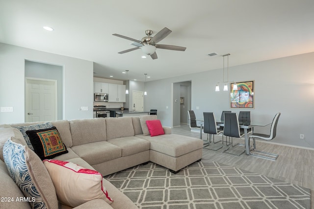 living room featuring hardwood / wood-style flooring, ceiling fan, and sink