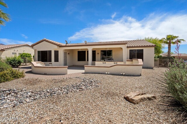 back of house with fence, stucco siding, and a tile roof