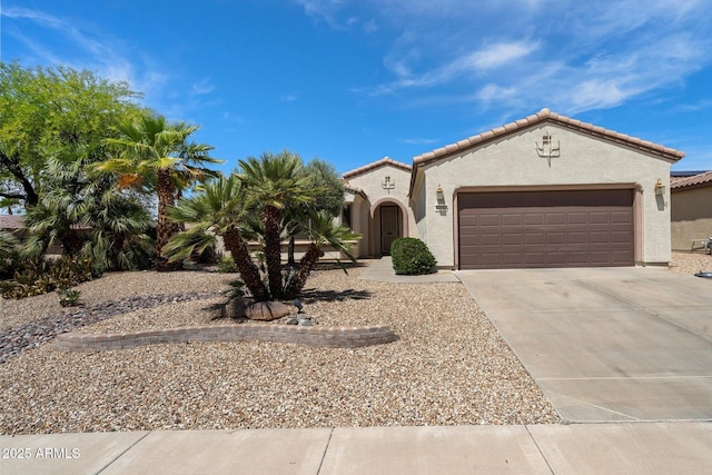 mediterranean / spanish house featuring concrete driveway, an attached garage, a tiled roof, and stucco siding